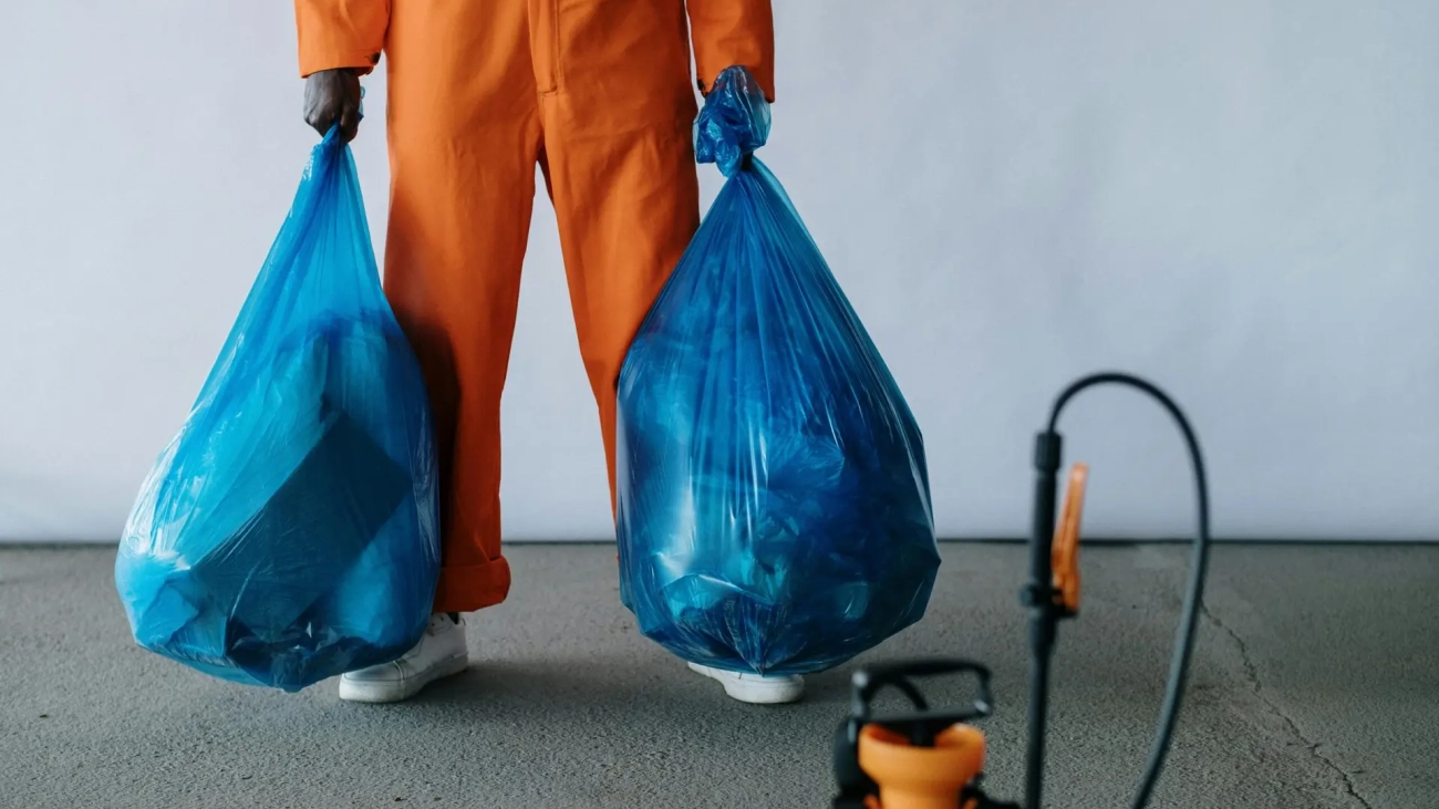 Photo by cottonbro studio: https://www.pexels.com/photo/man-in-orange-overalls-holding-blue-bags-9222613/
